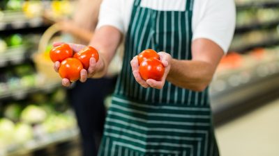 mid-section-of-worker-showing-vegetables-in-supermarket.jpg